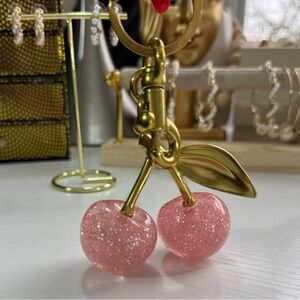 keychain or accessory featuring pink cherries made of a glittery material.